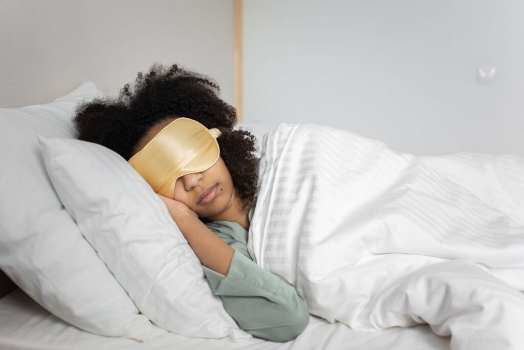 Kvinde sover med sovemaske i et hvidt soveværelse